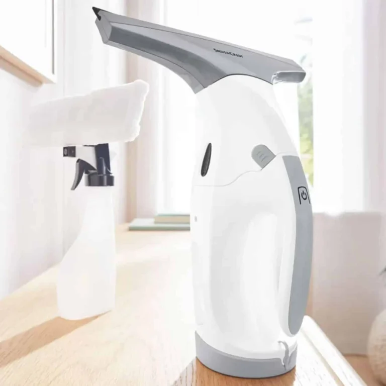 Nettoyeur de vitres sans fil Silvercrest de Lidl posé sur un plan de travail, avec son pulvérisateur à raclette microfibre en arrière-plan